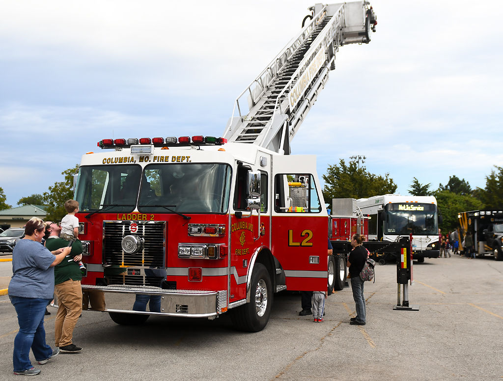 Topher Walters (green) carries his step-son, Silas Brunstrom,3, as Walter's mother Kristen Walters tries to take a picture of Brunstrom for the sensory-friendly Touch-a-Truck event